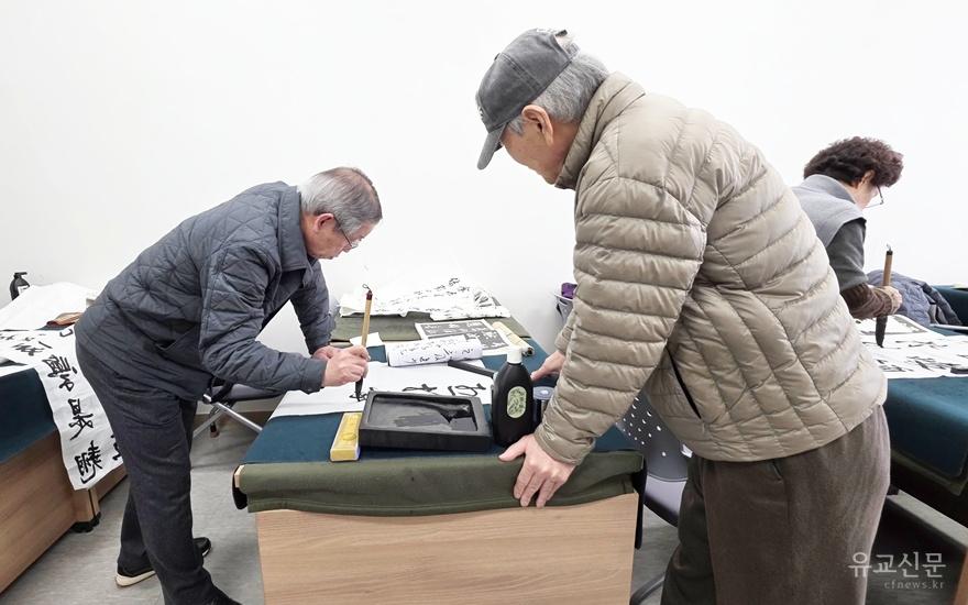 감주완 강사(왼쪽)가 서예 지도를 하고있다.jpg